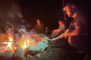 Three Biology students take a break and roast marshmallows around the campfire during a recent camping trip.