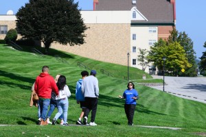 Student ambassador in a blue shirt leading a group of prospective students around campus.