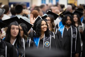 Many graduates sit at Mount Saint Mary College. One is waving. 