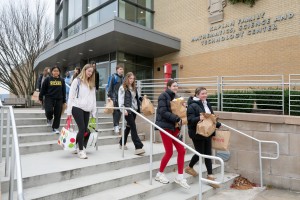 Mount Saint Mary College students from the First Year Experience (FYE) program carry bags of donated goods down the steps of the Kaplan Family Mathematics, Science and Technology Center on Tuesday, November 25. The students delivered the items to the camp