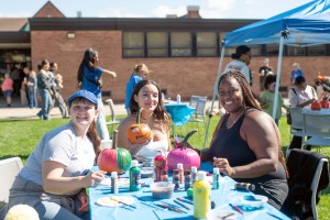 ALT: Three women smile and paint pumpkins at Mount Saint Mary College