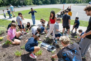 Mount Saint Mary College freshmen and Bishop Dunn Memorial School students work together to plant flowers in the Sensory Garden on the Mount campus as part of the college's First-Year Experience (FYE) program. 