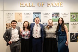 Men and women stand in a line smiling. The Mount Saint Mary College Athletic Hall of Fame Class of 2026 gathers in front of the permanent honors display following the induction ceremony on April 25, 2026. From left to right: Joseph Dolan ’20, and Michelle