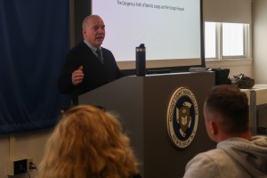 Man talks to crowd. Robert Miller, associate professor of Religious Studies at Mount Saint Mary College, presents “Climbing Mountains and Dodging Demons: The Dangerous Faith of Frassati and Longo” on Tuesday, April 21. 