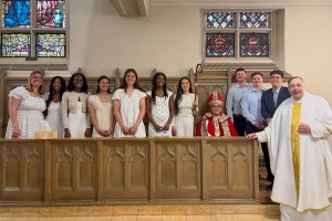 Men and women stand it a line in a church at Mount Saint Mary College. They are smiling. 
