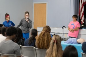 ALT: Mount Saint Mary College students fill an auditorium, the audience watching three women speak.