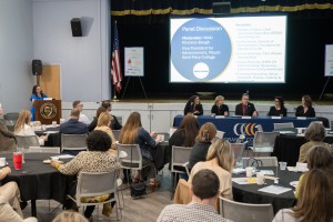Lots of people in an auditorium looking at a panel of men and women. Nikki Khurana-Baugh, Vice President for Advancement at Mount Saint Mary College, moderates the panel discussion during the “Partners in Purpose” forum. Seated from left to right are pane