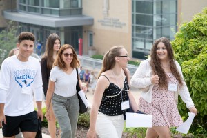 Incoming Mount Saint Mary College freshmen enjoyed making friends with their classmates and learning about what to expect in their upcoming college careers.  ALT: A group of college students and family members smiling as they walk up an outdoor walkway du