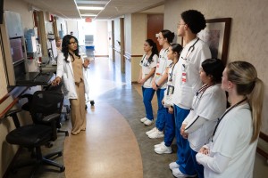Mount Saint Mary College nursing students work with a preceptor from Montefiore St. Luke’s Cornwall during the Spring 2026 semester. ALT: A female medical instructor in a white coat talks to a line of attentive nursing students wearing scrubs and stethosc