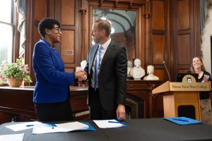 Evan Merkhofer, Vice President for Academic Affairs at Mount Saint Mary College, and Bettye Perkins, president and CEO of Today’s Students Tomorrow’s Teachers, shake hands after signing the paperwork officially naming the college as a TSTT partner. Jennif