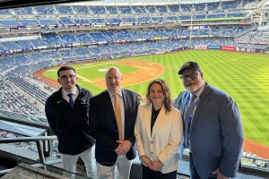Men and women smile at the camera with a baseball stadium behind them. Mount Saint Mary College faculty and staff, left to right: Kyle Teixeira, Assistant Athletic Director for Strategic Communications and Marketing; Michael L. Fox, J.D., Acting Dean of t