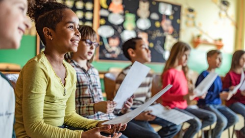 Children in a classroom reading from printed scripts