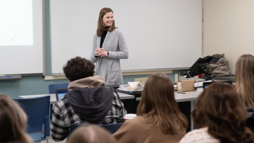 Image of professor teaching at the front of a classroom.